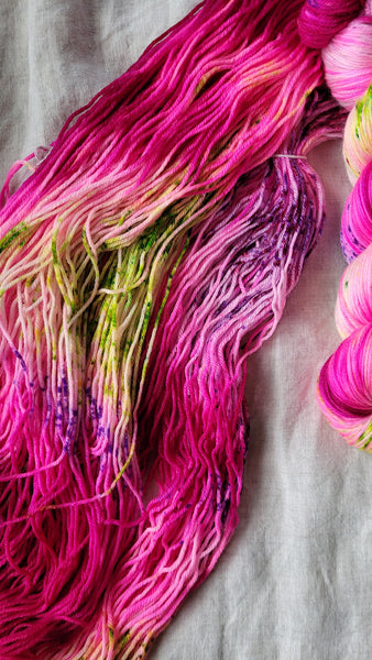 Skeins of hand dyed yarn in hot pink with green speckles