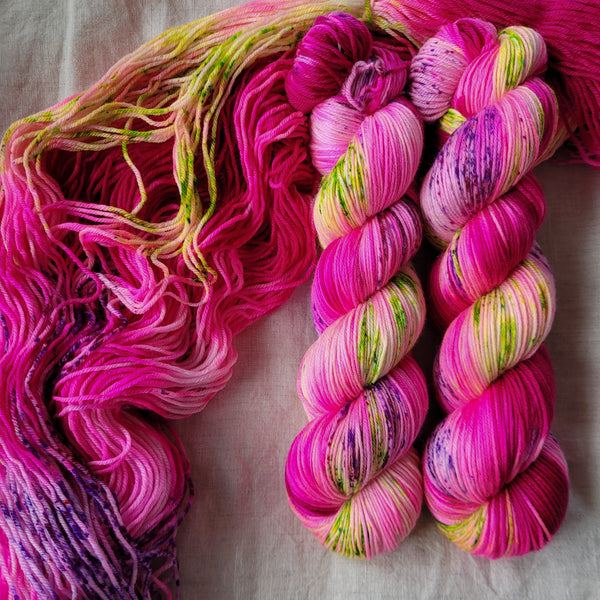 Skeins of hand dyed yarn in hot pink with green speckles