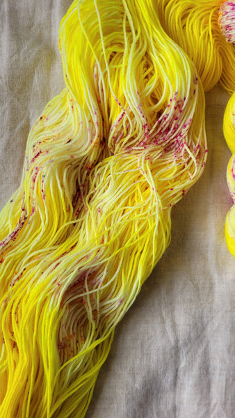 Skeins of hand dyed yarn in yellow with pink speckles